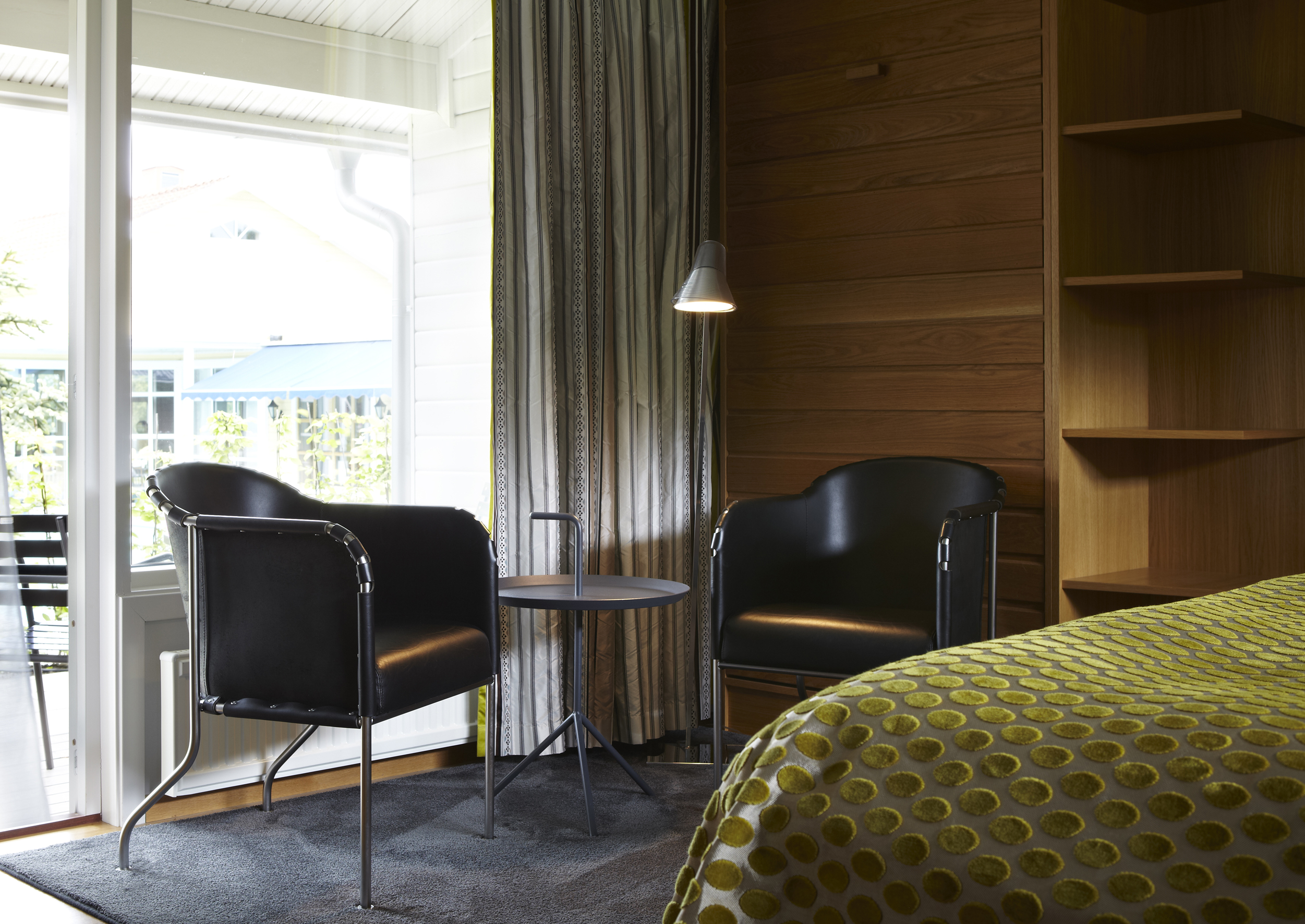 Vackert dubbelrum i villa 2. Två fåtöljer från Källemo. Dubbelsäng med grönt överkast på Hestraviken hotell och spa vid Isaberg i Småland